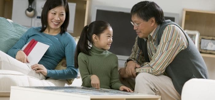 mother, father, and daughter talking in living room