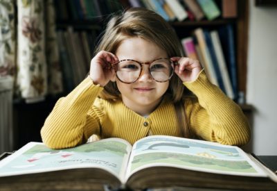 girl with glasses in front of open book