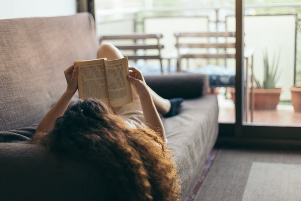 girl lying on couch reading a book
