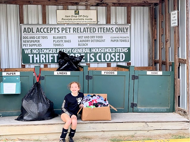 girl with box of stuffed toys in front of animal shelter